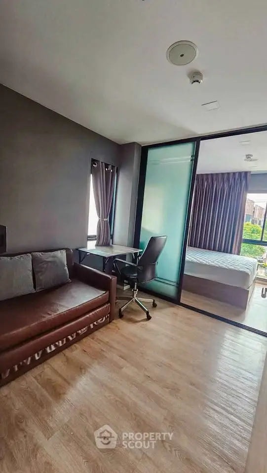 Modern studio apartment with cozy living area and bedroom, featuring sleek furniture and natural light.