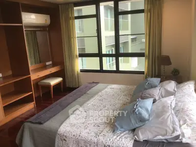 Spacious bedroom with large windows and elegant decor in modern apartment.