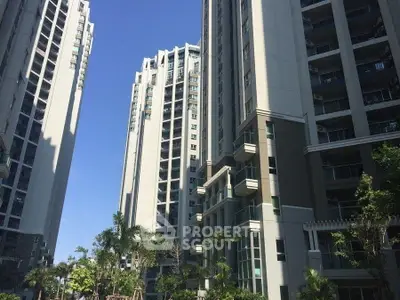 Modern high-rise residential buildings with lush greenery and clear blue sky.