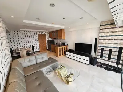 Modern living room with open kitchen, stylish decor, and ample natural light.