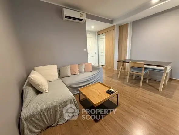 Modern living room with cozy sofa and dining area, featuring sleek wooden flooring.