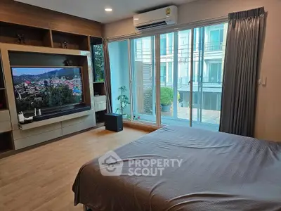 Modern bedroom with large TV and balcony access in stylish apartment