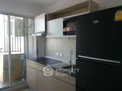 Modern kitchen with sleek cabinets and large fridge in a bright apartment