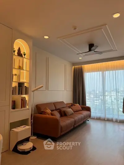 Elegant living room with leather sofa, modern lighting, and large window with city view.