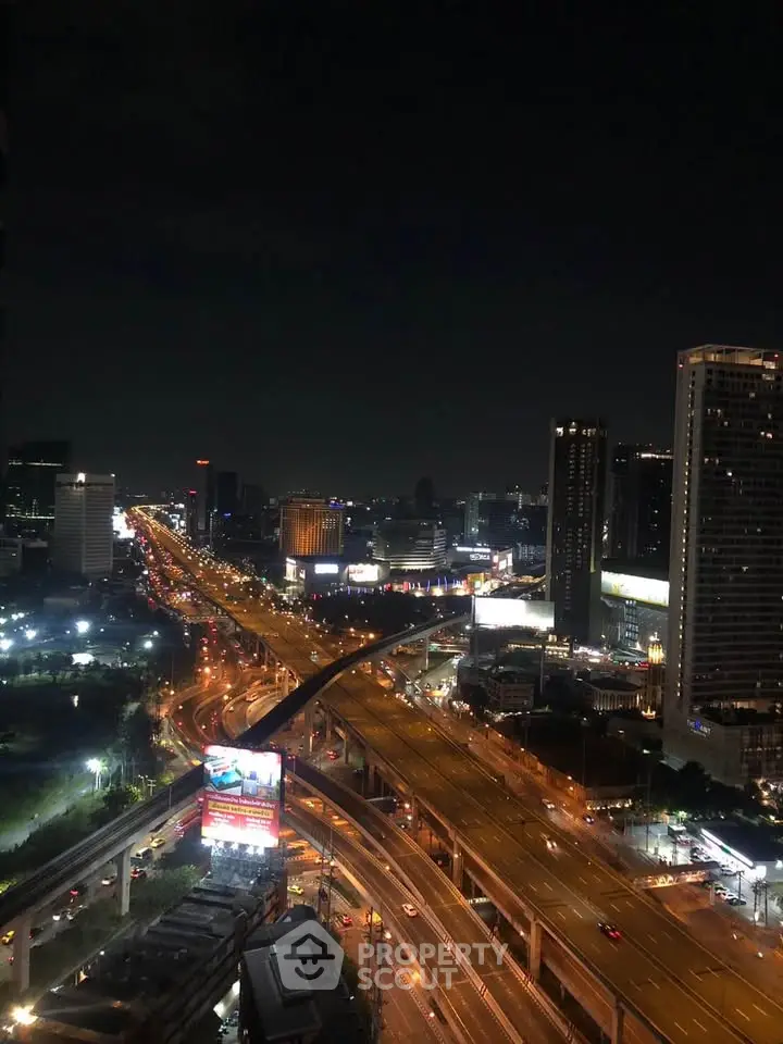 Stunning nighttime cityscape view with illuminated highways and skyscrapers.