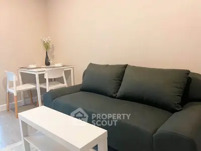 Modern living room with sleek black sofa and minimalist dining area, perfect for urban living.