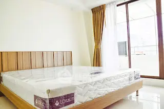 Spacious bedroom with large windows and natural light in modern apartment.