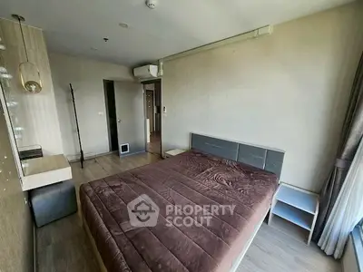 Spacious bedroom with modern decor and large window for natural light.