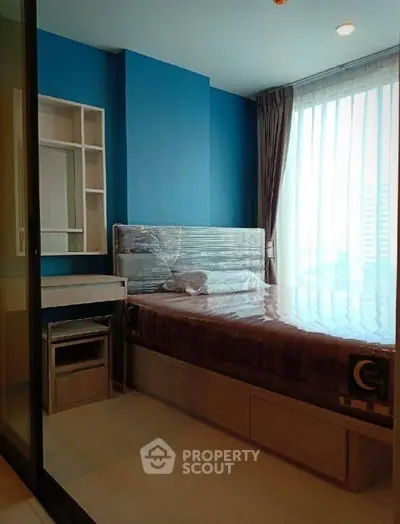 Modern bedroom with large window and stylish blue accent wall in a contemporary apartment.