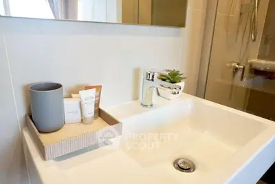 Modern bathroom sink with stylish faucet and elegant toiletries in a chic real estate property.
