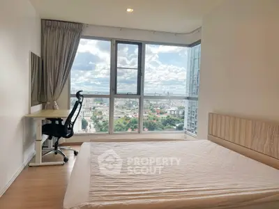 Bright bedroom with large window offering stunning city view, featuring a desk and modern chair for a perfect work-from-home setup.