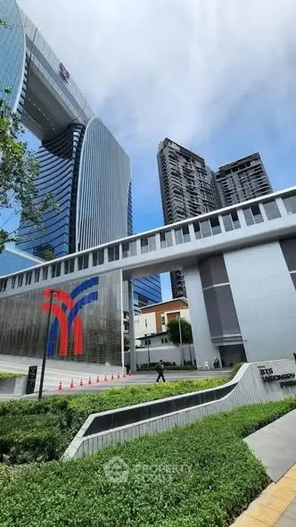 Modern high-rise building with sleek architecture and lush landscaping in urban setting.