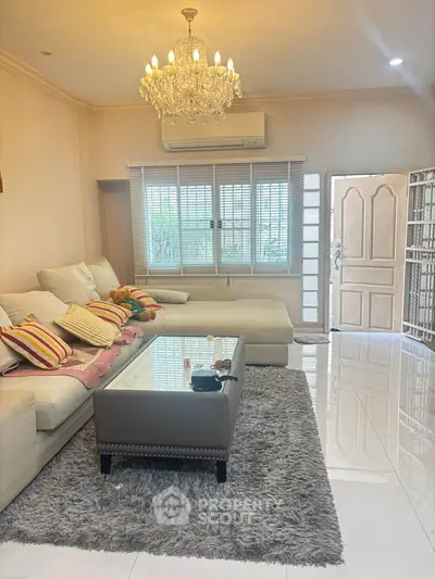 Elegant living room with chandelier, plush sofa, and modern decor in a cozy home setting.
