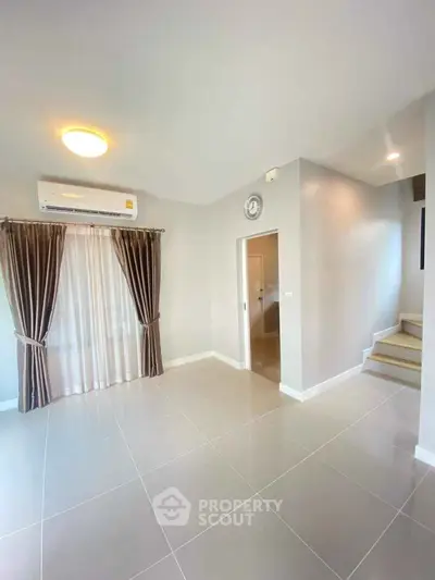 Spacious modern living room with elegant curtains and staircase, perfect for family gatherings.