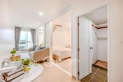 Modern apartment with cozy living room and bedroom, featuring sliding doors and bright decor.