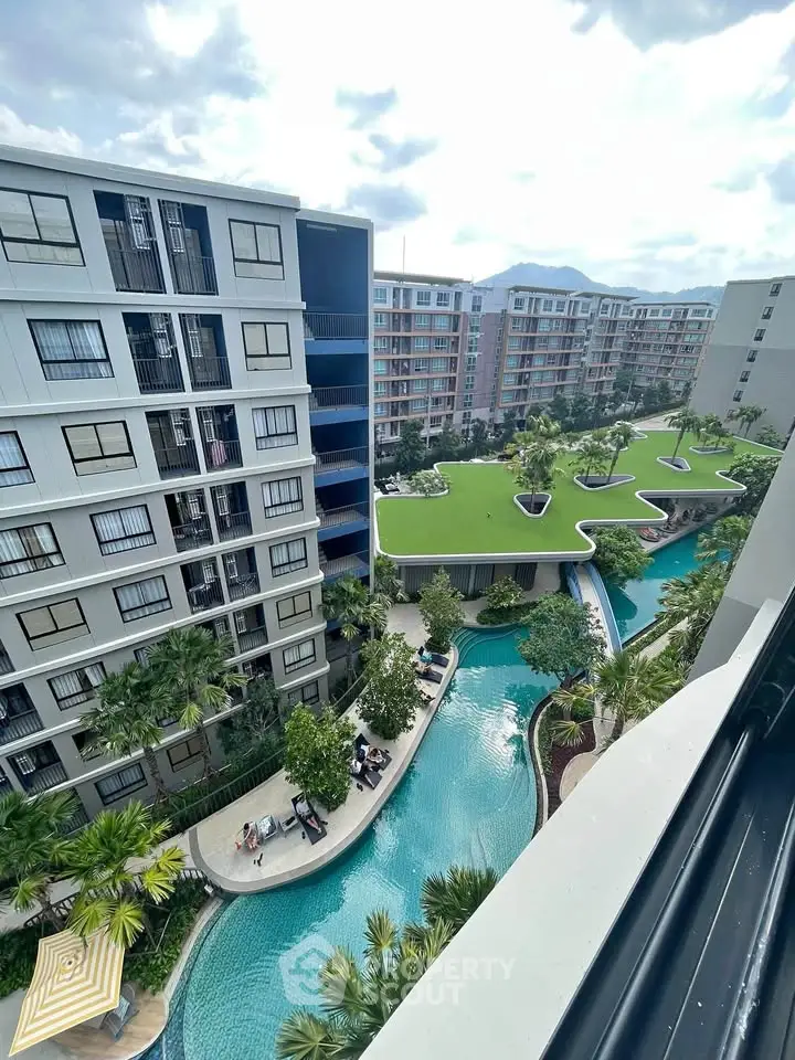 Modern apartment complex with lush green rooftop and stunning pool view.