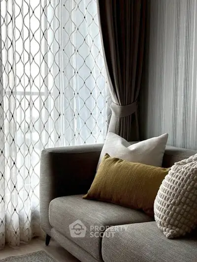 Elegant living room with stylish sofa and decorative pillows, featuring modern curtains and natural light.
