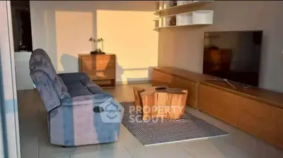 Modern living room with stylish furniture and large TV, bathed in warm sunlight.