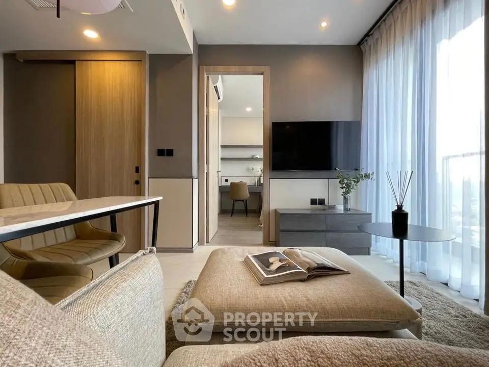 Modern living room with stylish decor and open view to study area, featuring neutral tones and elegant furnishings.