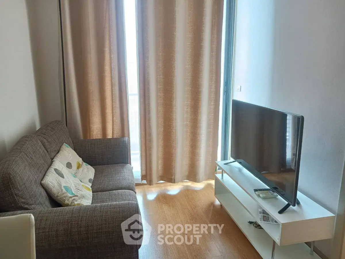 Cozy living room with modern sofa and flat-screen TV, perfect for relaxation.
