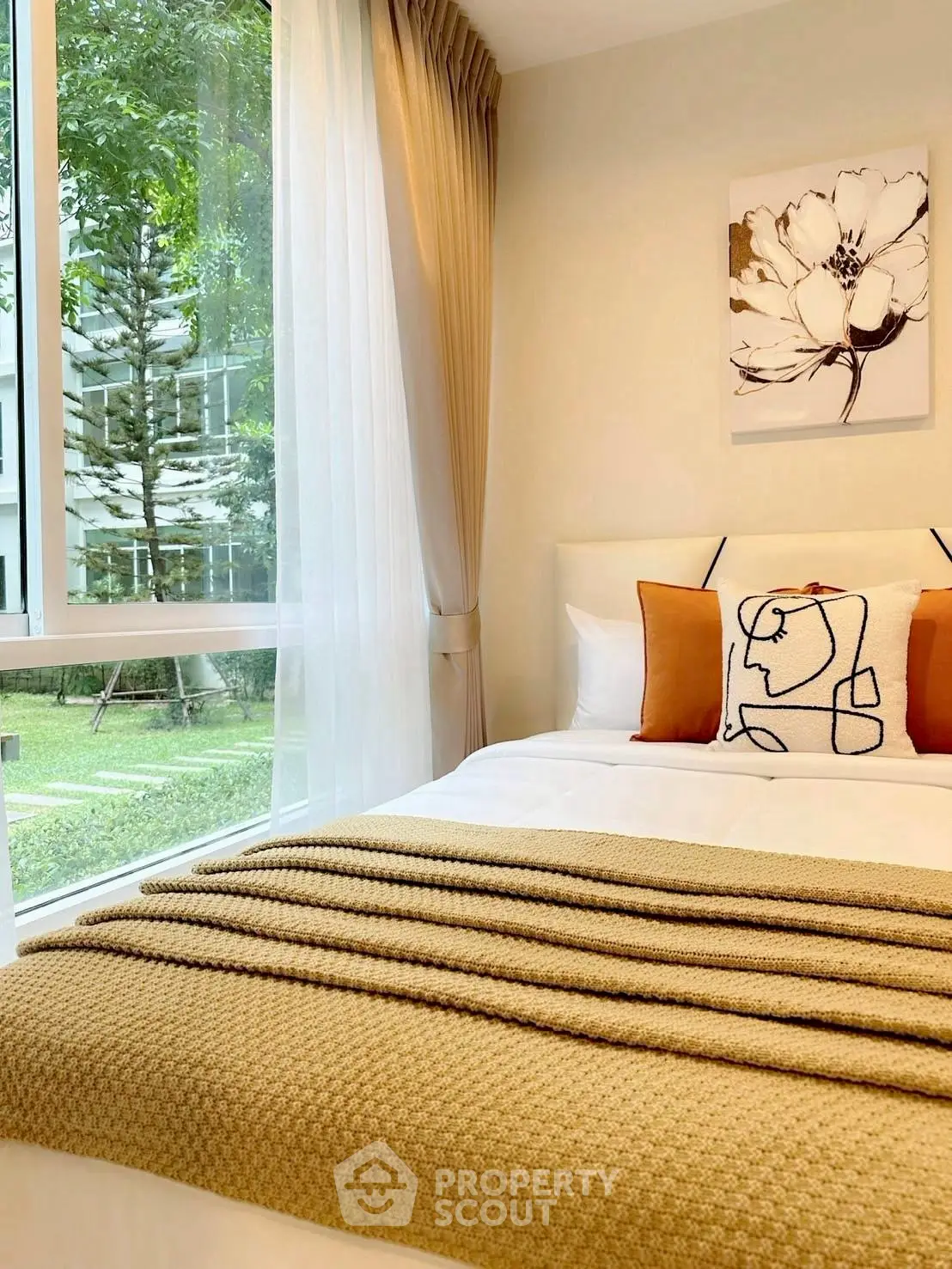Cozy bedroom with large window and garden view, featuring elegant decor and warm tones.