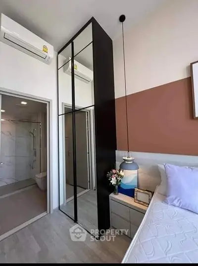Modern bedroom with sleek mirrored wardrobe and ensuite bathroom