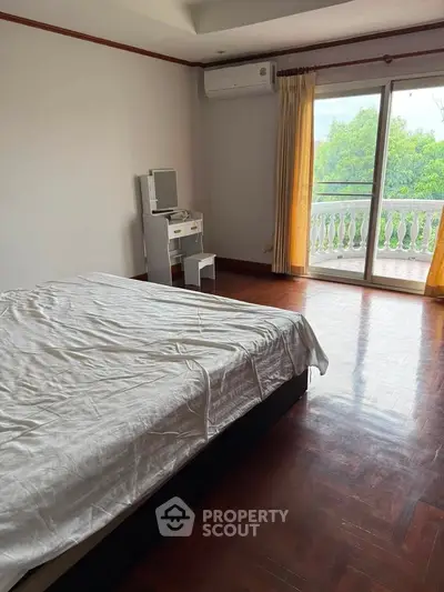 Spacious bedroom with balcony access and natural light, featuring a cozy bed and air conditioning.