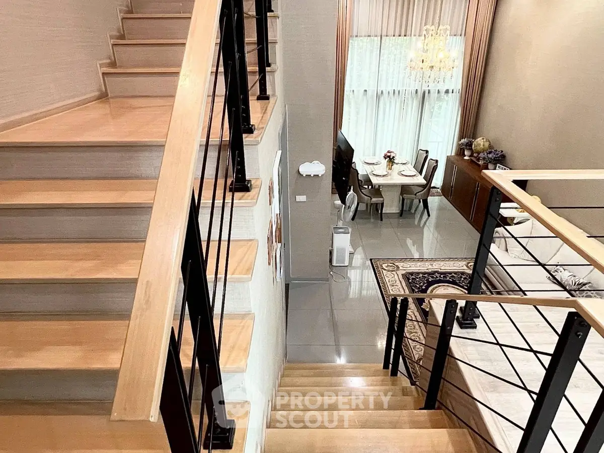Elegant staircase leading to a modern dining area with high ceilings and stylish decor.