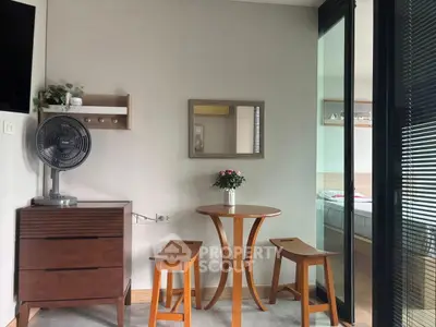 Cozy dining nook with wooden table and stools, adjacent to a bedroom with sliding glass doors.