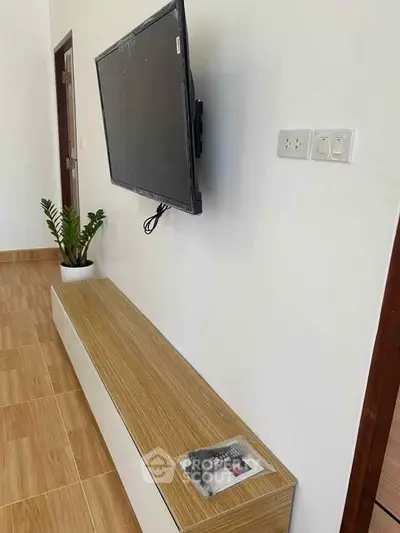 Modern living room with wall-mounted TV and sleek wooden console.