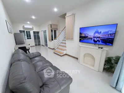 Spacious living room with modern decor and large TV, perfect for relaxation.