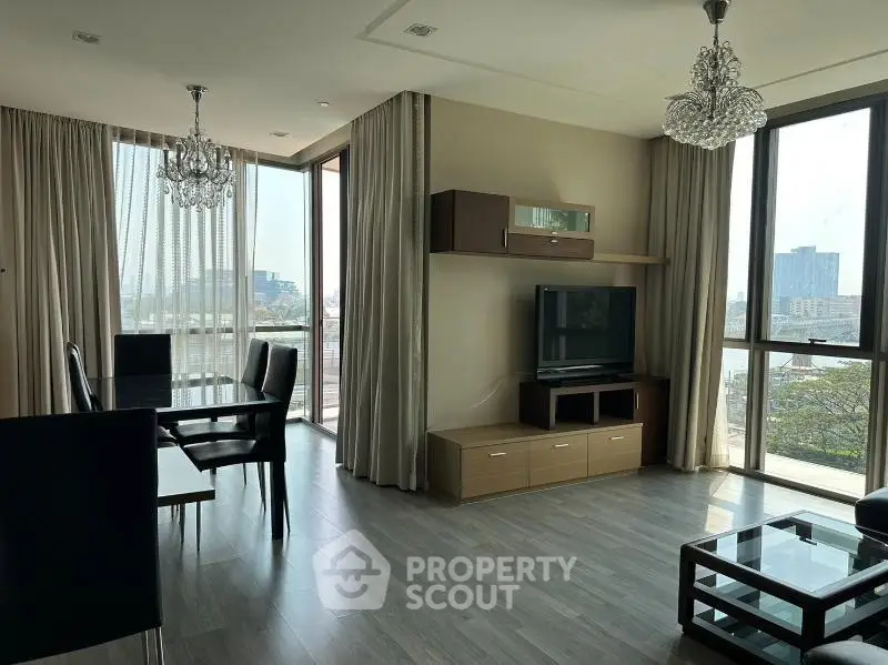 Spacious modern living room with elegant chandeliers and large windows offering city views.