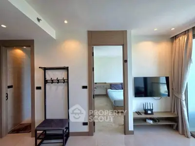 Modern apartment interior with TV, coat rack, and bedroom view