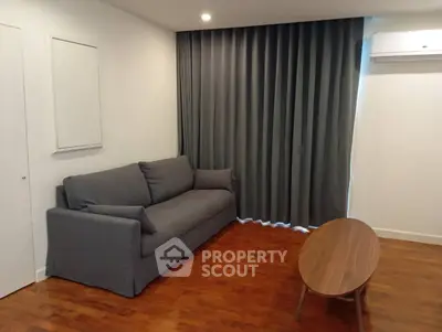 Cozy living room with modern gray sofa and wooden coffee table on polished hardwood floor.