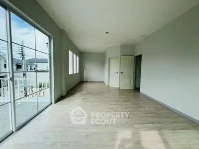Spacious empty room with large windows and wooden flooring