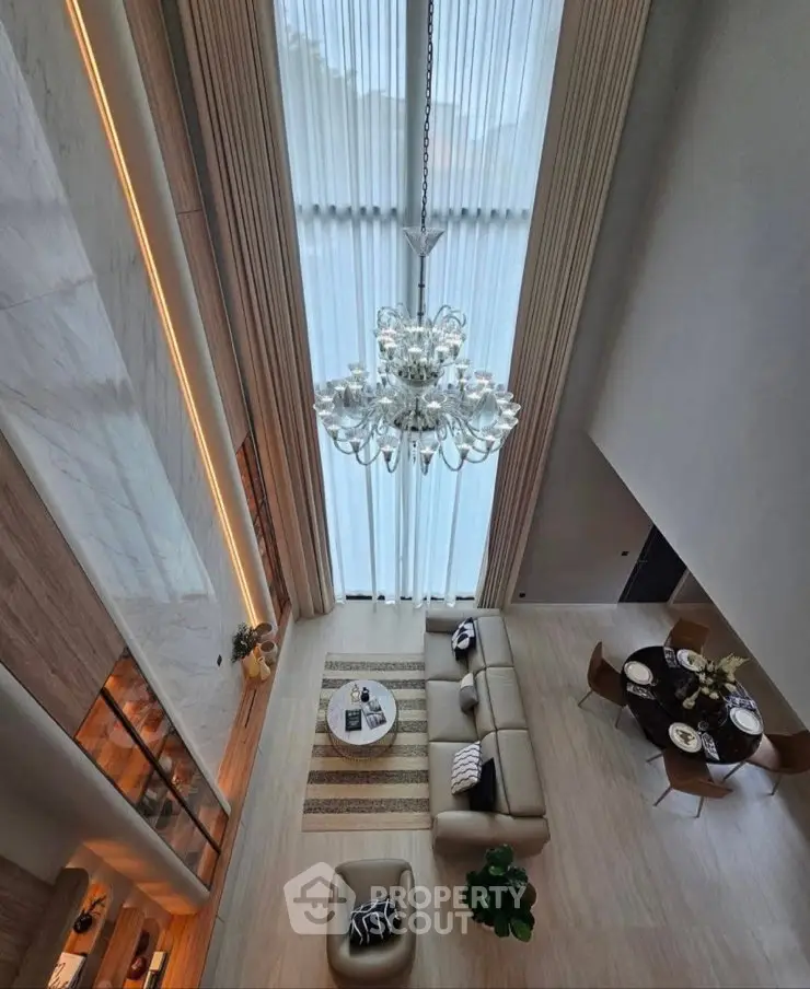 Luxurious high-ceiling living room with elegant chandelier and modern decor