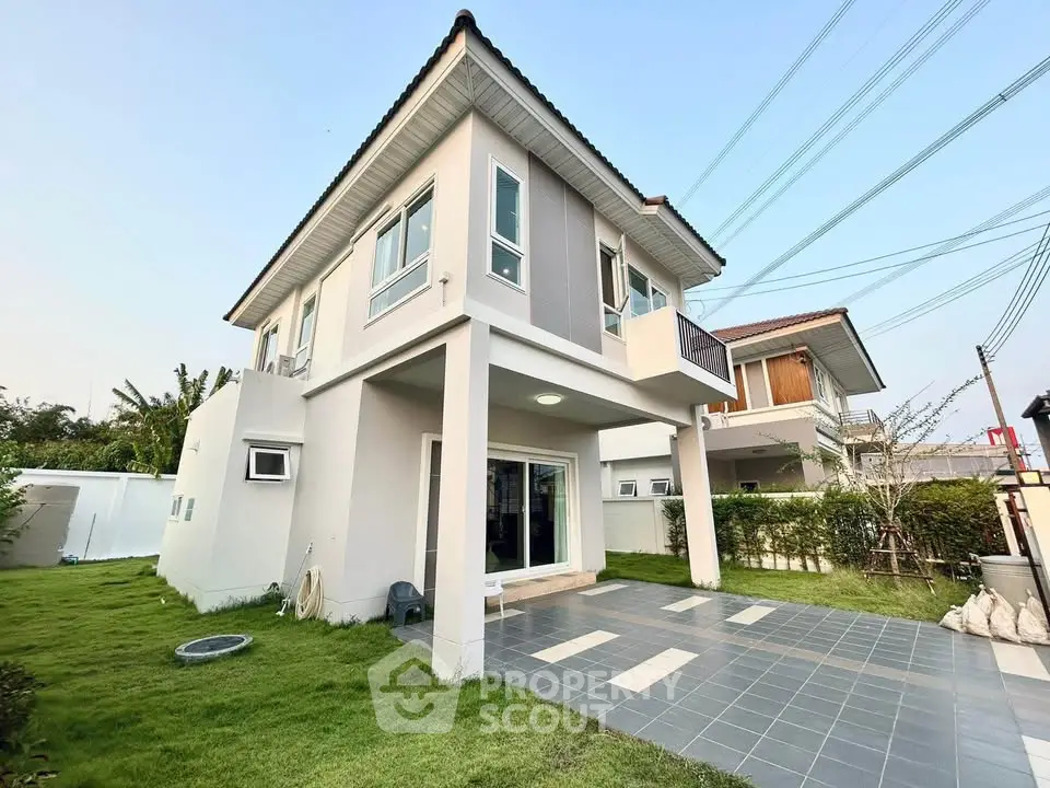 Modern two-story house with spacious patio and lush green lawn, perfect for family living.