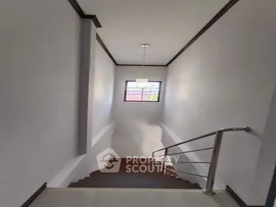 Elegant staircase with modern railing and natural light from window