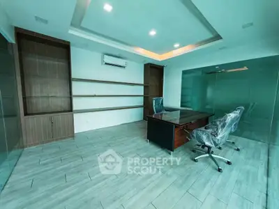 Modern office space with sleek design and glass walls, featuring a desk and chairs.