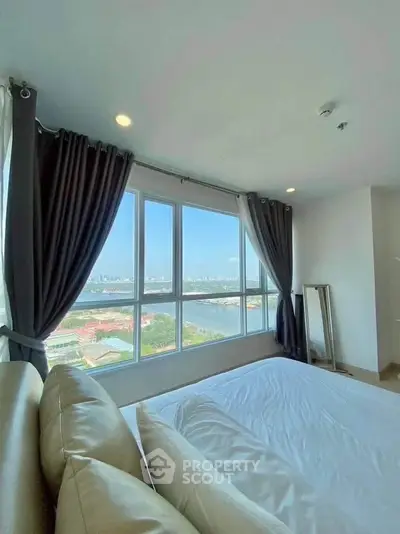 Luxurious bedroom with stunning city and river view from large windows, featuring elegant curtains and cozy bedding.