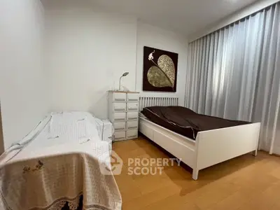 Cozy bedroom with wooden flooring, modern art, and ample natural light.