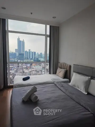 Modern bedroom with city view, featuring large windows and cozy bedding.