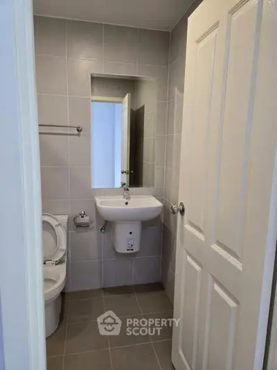 Compact modern bathroom with sleek fixtures and neutral tiles, perfect for efficient space utilization.