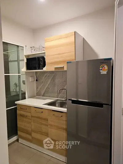 Modern compact kitchen with stainless steel fridge and wooden cabinets