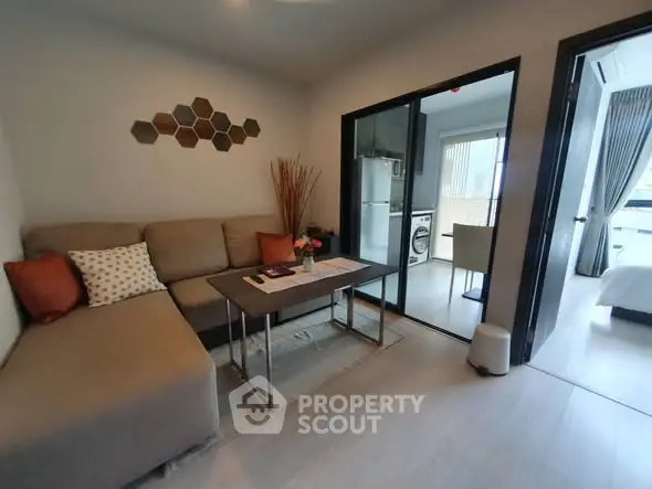 Modern living room with stylish decor and open layout leading to kitchen and bedroom.