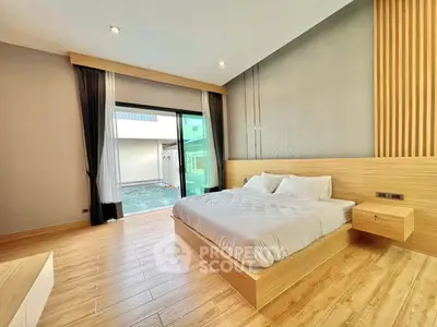 Modern bedroom with wooden flooring and large sliding glass doors to balcony
