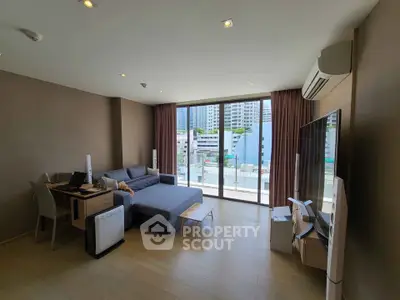 Spacious modern living room with large windows and city view, featuring sleek furniture and air conditioning.