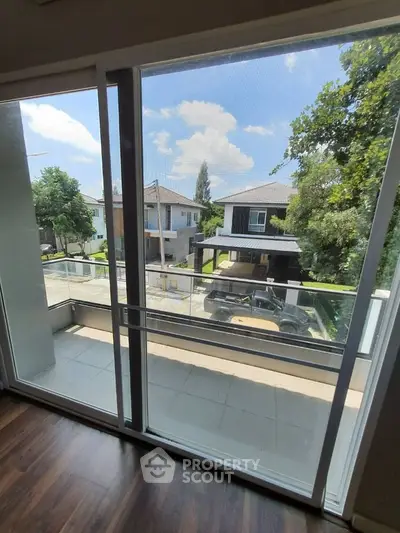 Spacious balcony with serene neighborhood view and lush greenery.