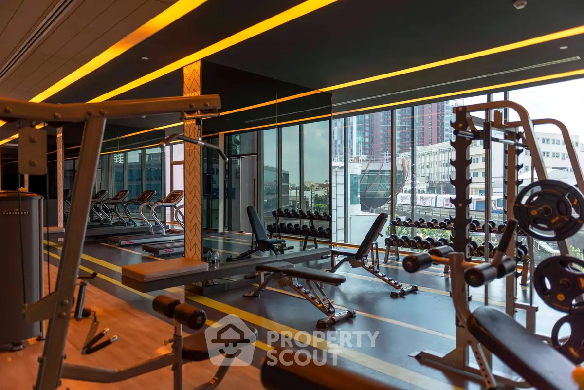 Luxurious gym with modern equipment and city view in upscale residential building.