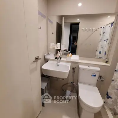 Modern bathroom with sleek fixtures and neutral tones, featuring a compact sink and toilet.